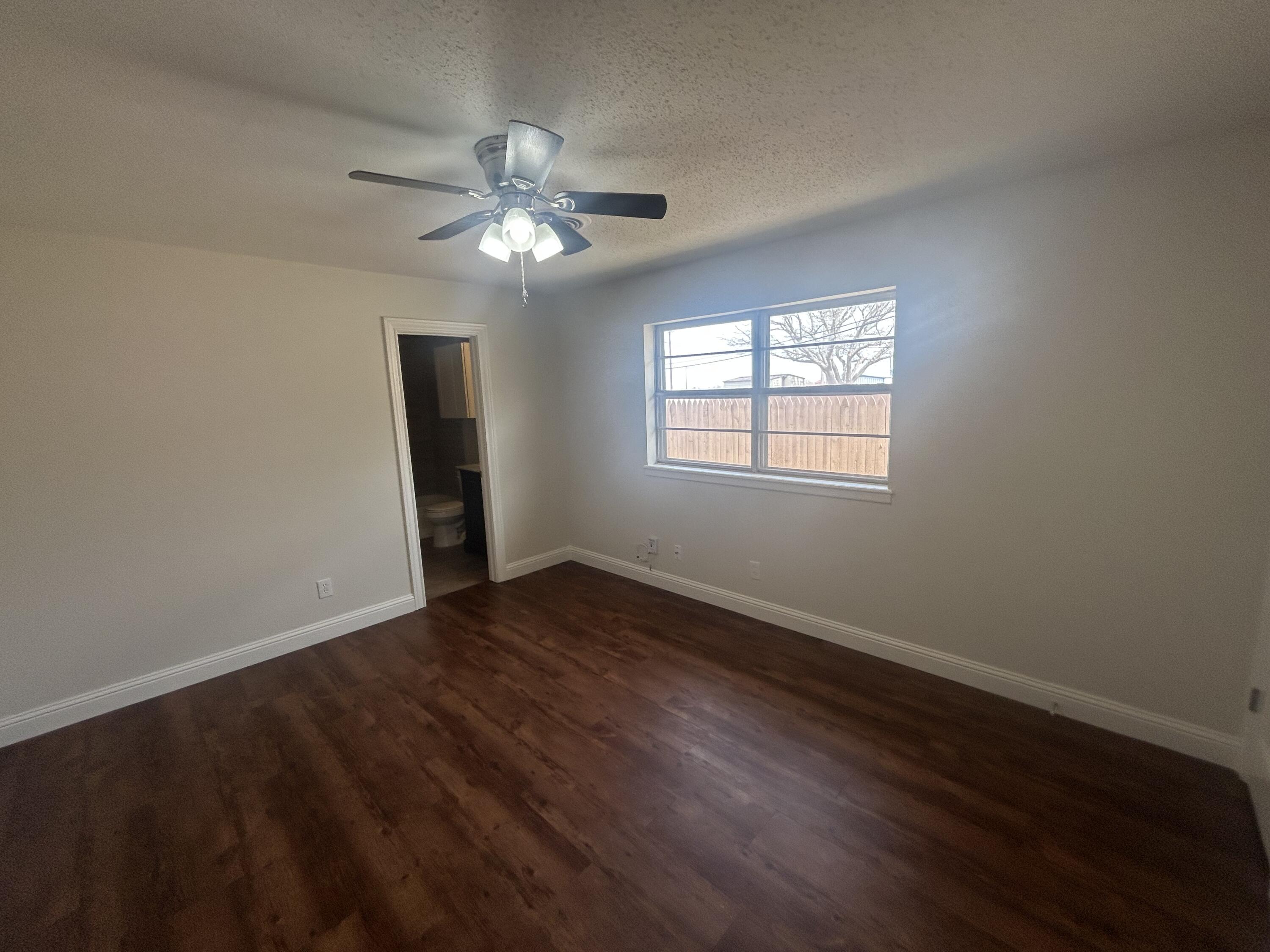 111 Bobby Street Levelland, TX 79336 - Photo 10 of 25 a view of an empty room with wooden floor and a window