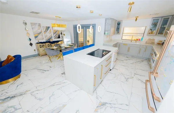 a kitchen with granite countertop a refrigerator a sink and white cabinets