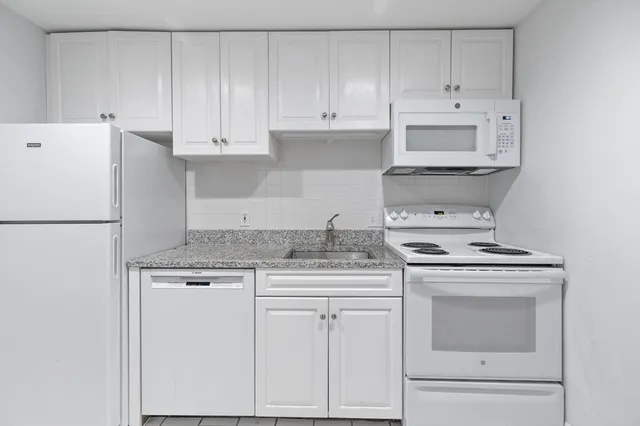 a kitchen with granite countertop white cabinets and white appliances