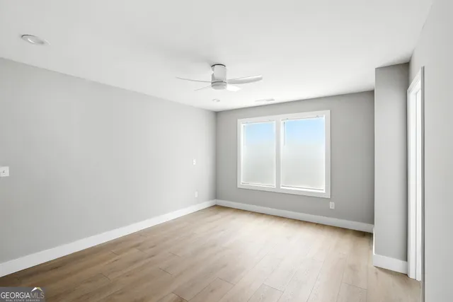 an empty room with wooden floor and ceiling fan