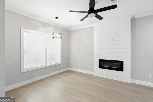 a view of an empty room with a window and kitchen view