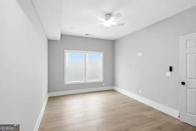 an empty room with wooden floor and windows