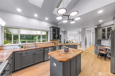 a kitchen with a stove a sink a counter space and living room view