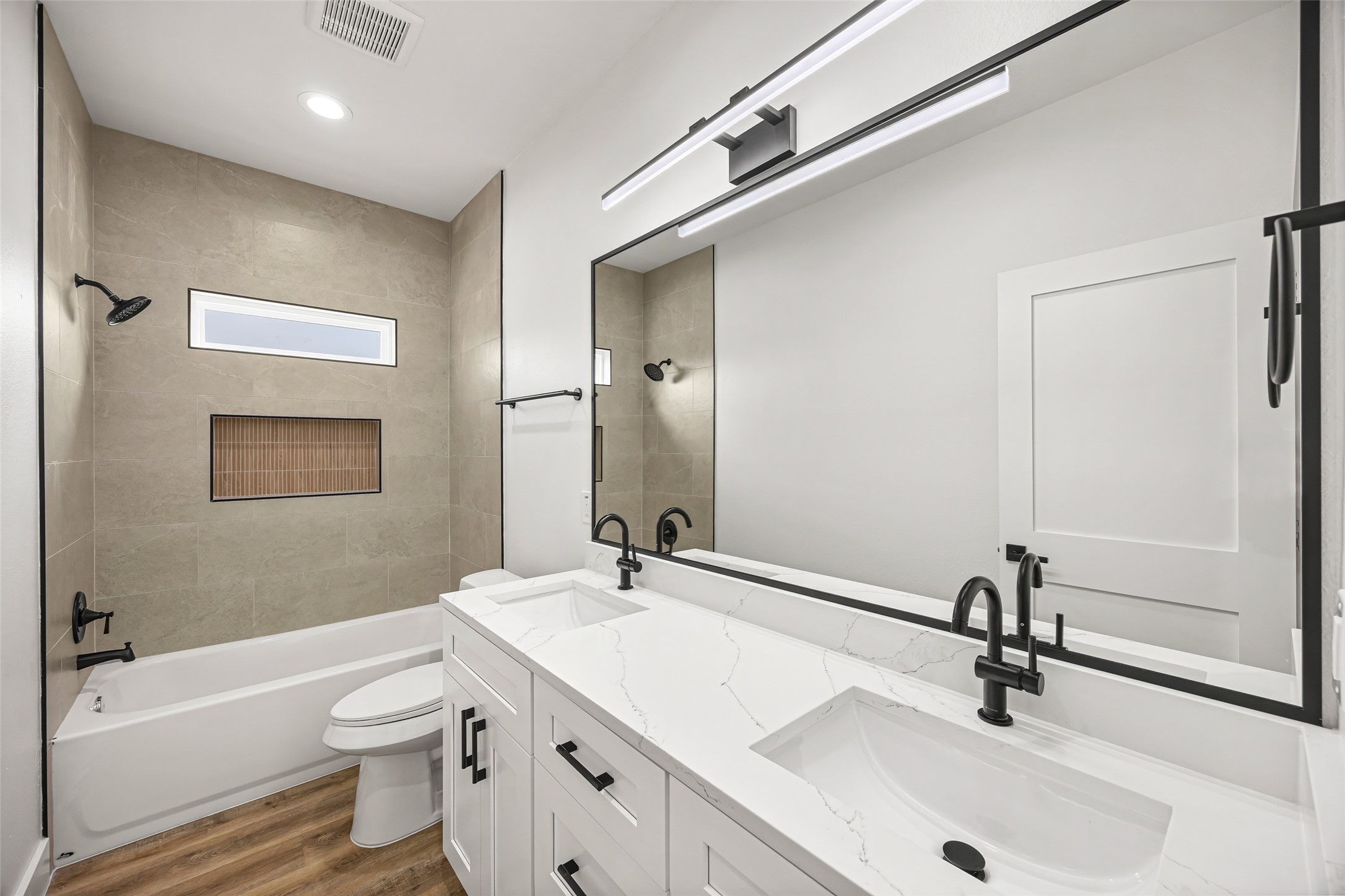 1807 Waco Street Dayton, TX 77535 - Photo 22 of 26 Quartz dual-sink vanity with matte black fixtures and oversized framed mirror.