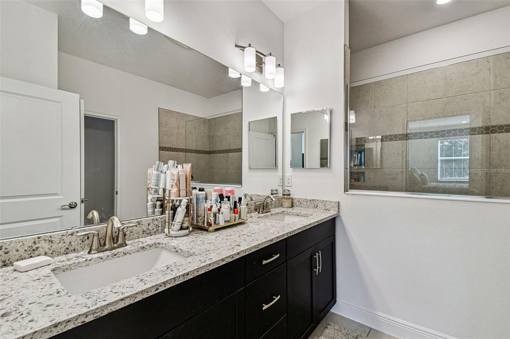 1039 Davis Heather Circle Seffner, FL 33584 - Photo 17 of 27 a bathroom with a granite countertop sink a large mirror and a shower