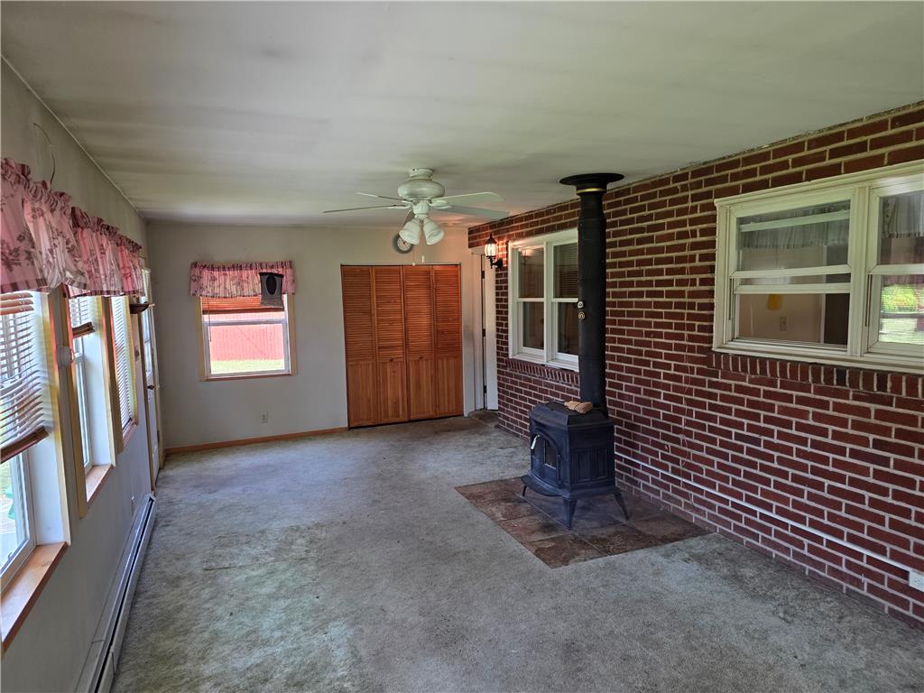 3134 Roxford Road Allentown, PA 18103 - Photo 19 of 34 A cozy, sun-filled room featuring a wood-burning stove and multiple windows.