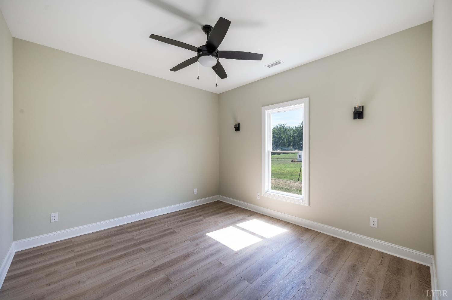 272 Marshall Mill Road Gladys, VA 24554 - Photo 29 of 71 an empty room with wooden floor ceiling fan and windows