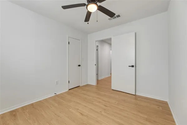 an empty room with a ceiling fan and wooden floor