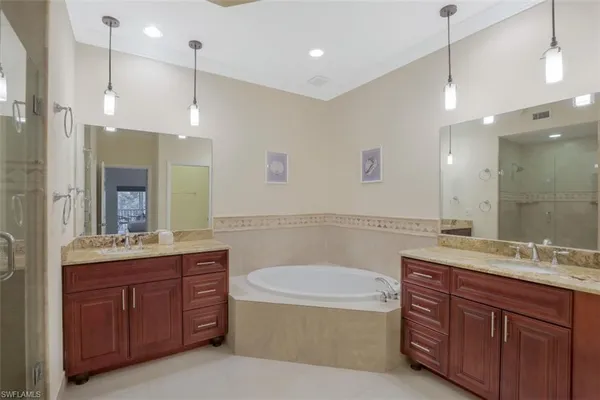 a bathroom with a tub a sink double vanity and a mirror