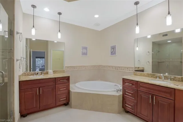 a bathroom with a tub a sink double vanity and a mirror