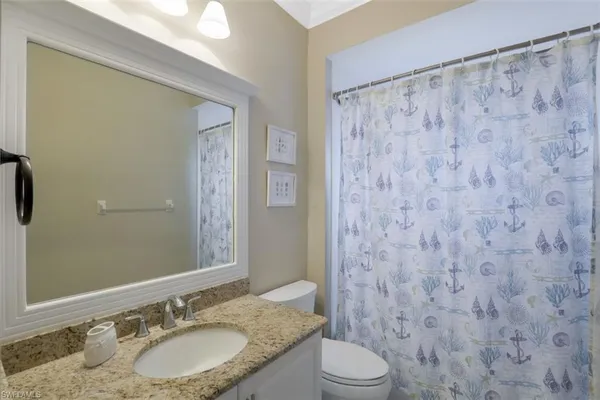 a bathroom with a granite countertop sink a toilet and a mirror