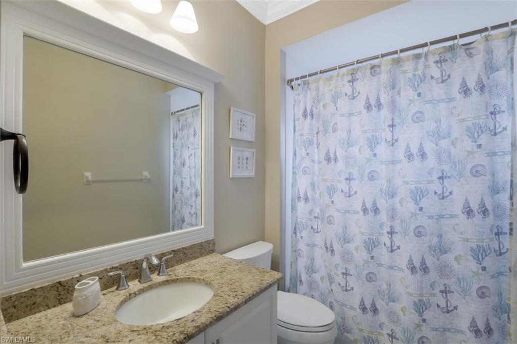 1240 Shady Rest Lane, Unit 102 Naples, FL 34103 - Photo 17 of 23 a bathroom with a granite countertop sink a toilet and a mirror