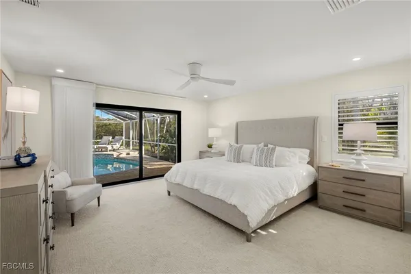 a bedroom with a bed a mirror on dresser and a large window