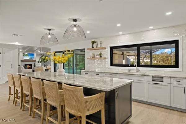 a kitchen with stainless steel appliances kitchen island granite countertop a table chairs and a refrigerator