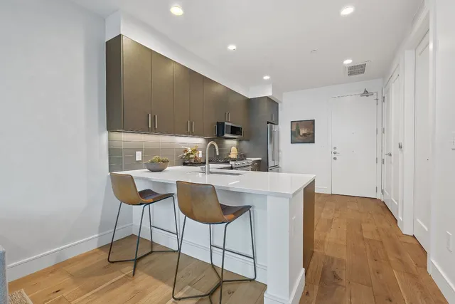 a kitchen with stainless steel appliances kitchen island granite countertop a sink and a refrigerator