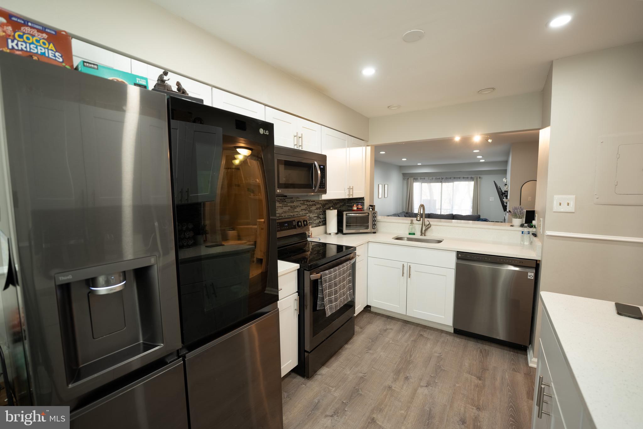 15 Pickering Court, Unit 1502 Germantown, MD 20874 - Photo 8 of 17 a kitchen with a refrigerator stainless steel appliances wooden floor and cabinets