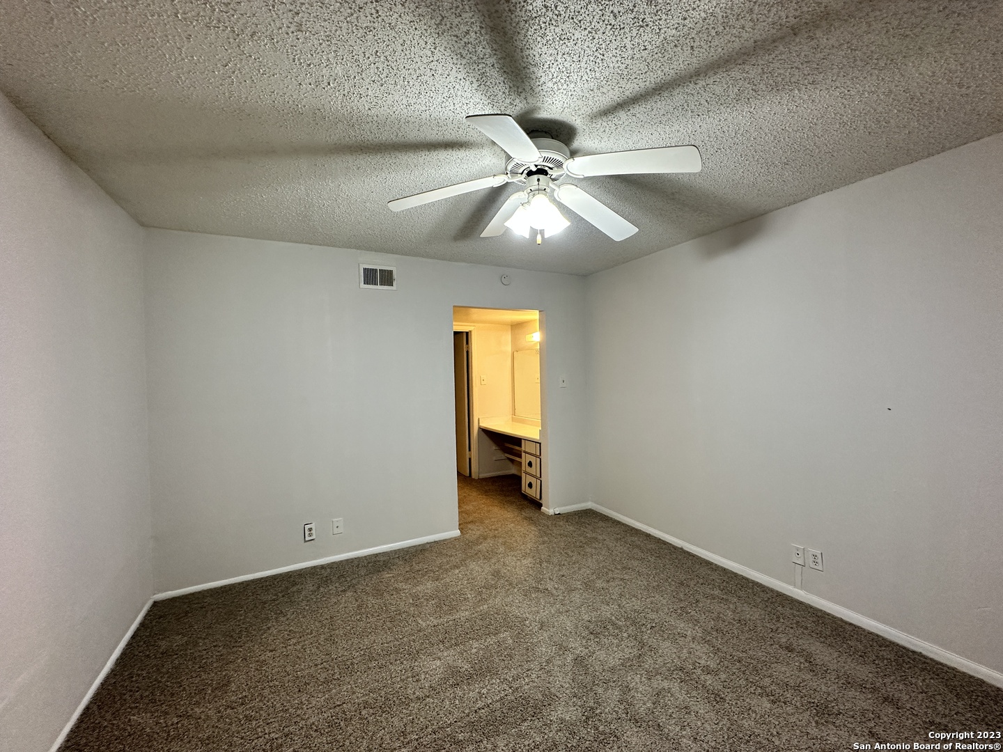 an empty room with a ceiling fan and wooden floor