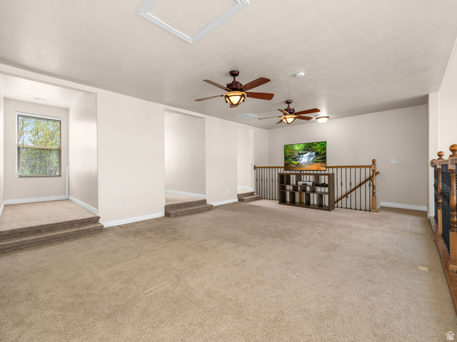 255 East 1200 North Mapleton, UT 84664 - Photo 18 of 37 Spacious carpeted room featuring multiple ceiling fans, a built-in entertainment stand, and a staircase with wood and metal balusters