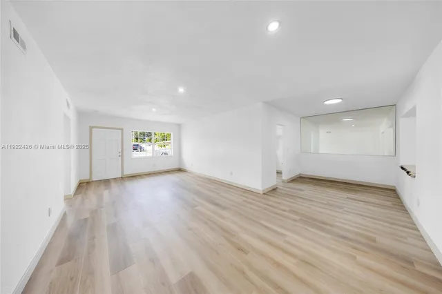 a view of an empty room with a window and wooden floor