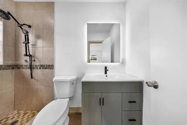 a bathroom with a sink a toilet a mirror and shower