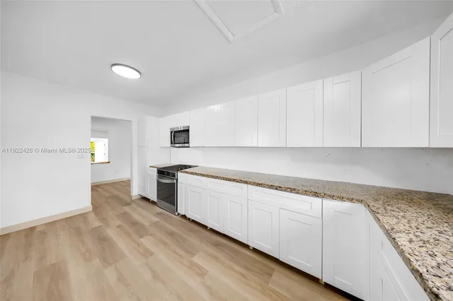 a kitchen with granite countertop white cabinets and white appliances