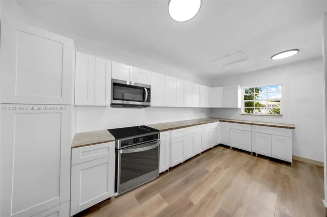 a kitchen with stainless steel appliances white cabinets and a wooden floor