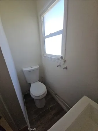 a white toilet sitting in a bathroom next to a window