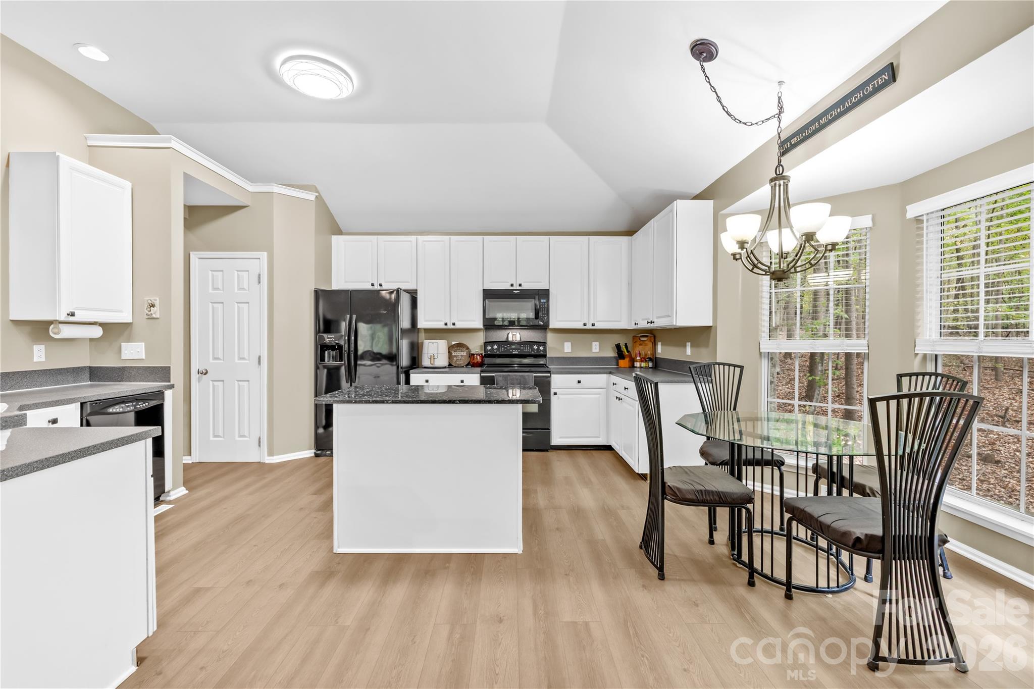11113 Asbury Chapel Road Huntersville, NC 28078 - Photo 22 of 43 a kitchen with stainless steel appliances granite countertop a stove top oven a sink dishwasher a dining table and chairs with wooden floor