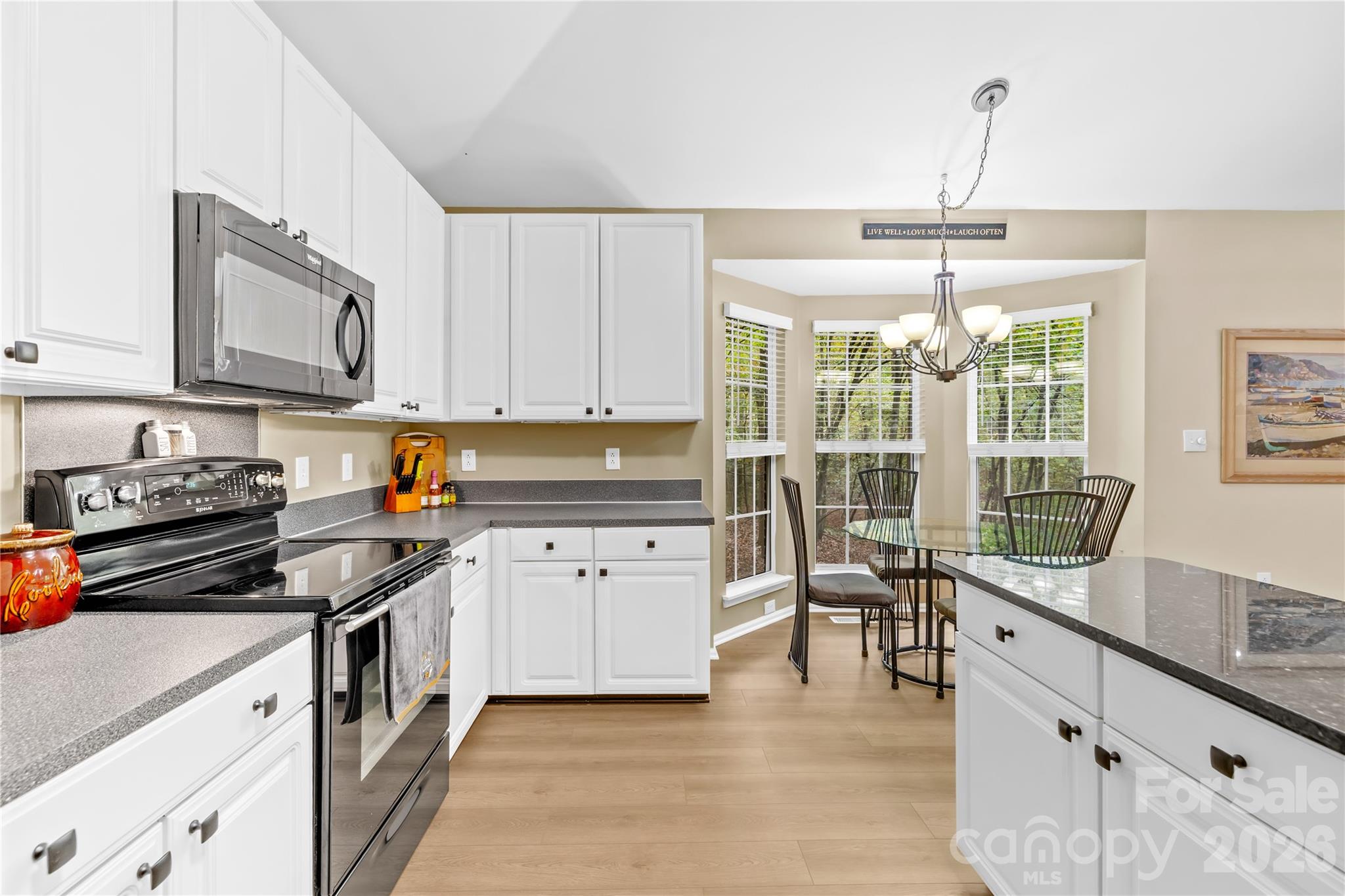 11113 Asbury Chapel Road Huntersville, NC 28078 - Photo 24 of 43 a kitchen with granite countertop a stove a sink a dining table and chairs with wooden floor
