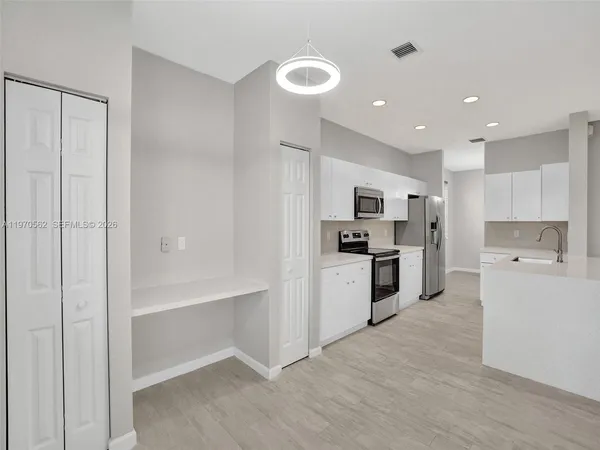 a kitchen with white cabinets and stainless steel appliances