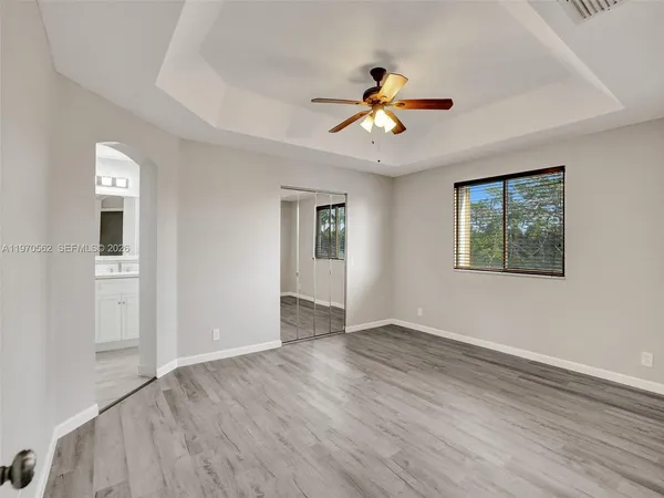 a view of an empty room with a window and wooden floor