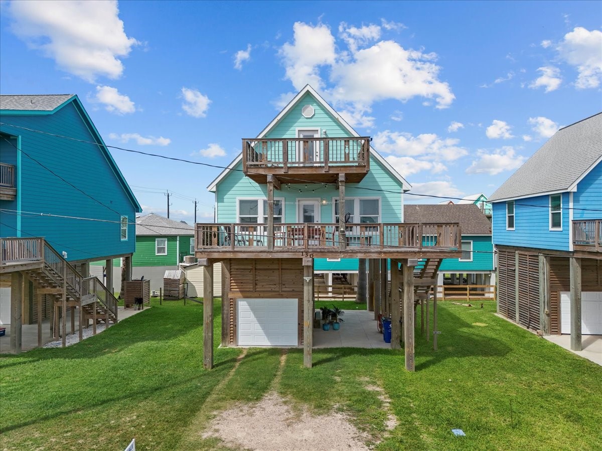 130 Beachcomber Avenue Surfside Beach, TX 77541 - Photo 2 of 33 Elevated coastal home with a spacious deck, bright exterior, and ample parking underneath. Ideal for beachside living.