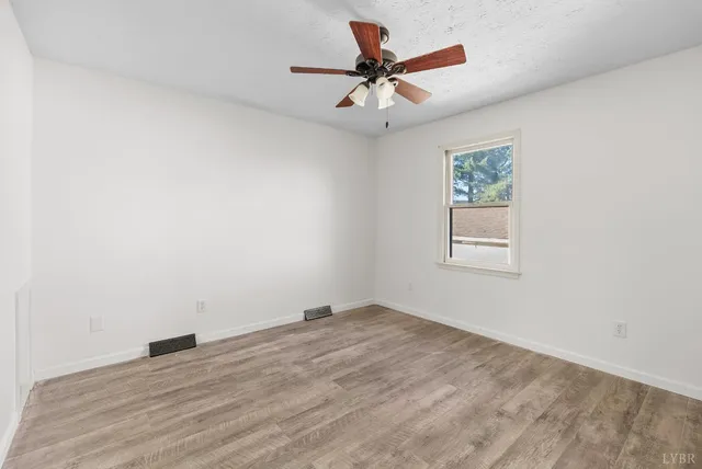 an empty room with a window and a fan