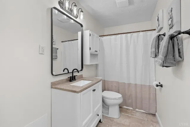 a bathroom with a granite countertop sink a toilet a mirror and shower