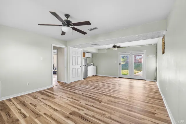 a view of empty room with wooden floor and ceiling fan