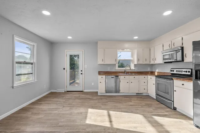 a kitchen with granite countertop a stove a sink and a refrigerator