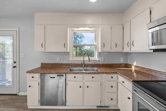 a kitchen with granite countertop a sink window and cabinets