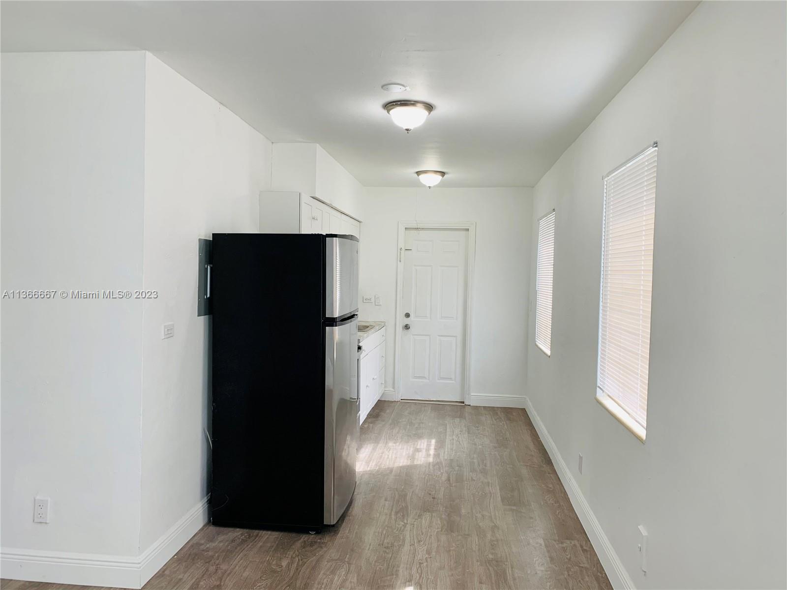738 Northeast 86th Street, Unit 8 Miami, FL 33138 - Photo 4 of 10 an empty room with wooden floor and windows