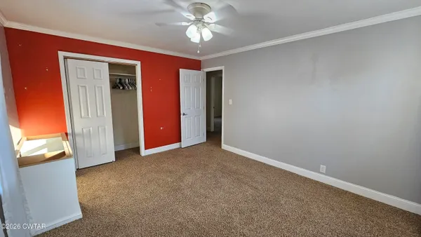 an empty room with closet and a chandelier fan
