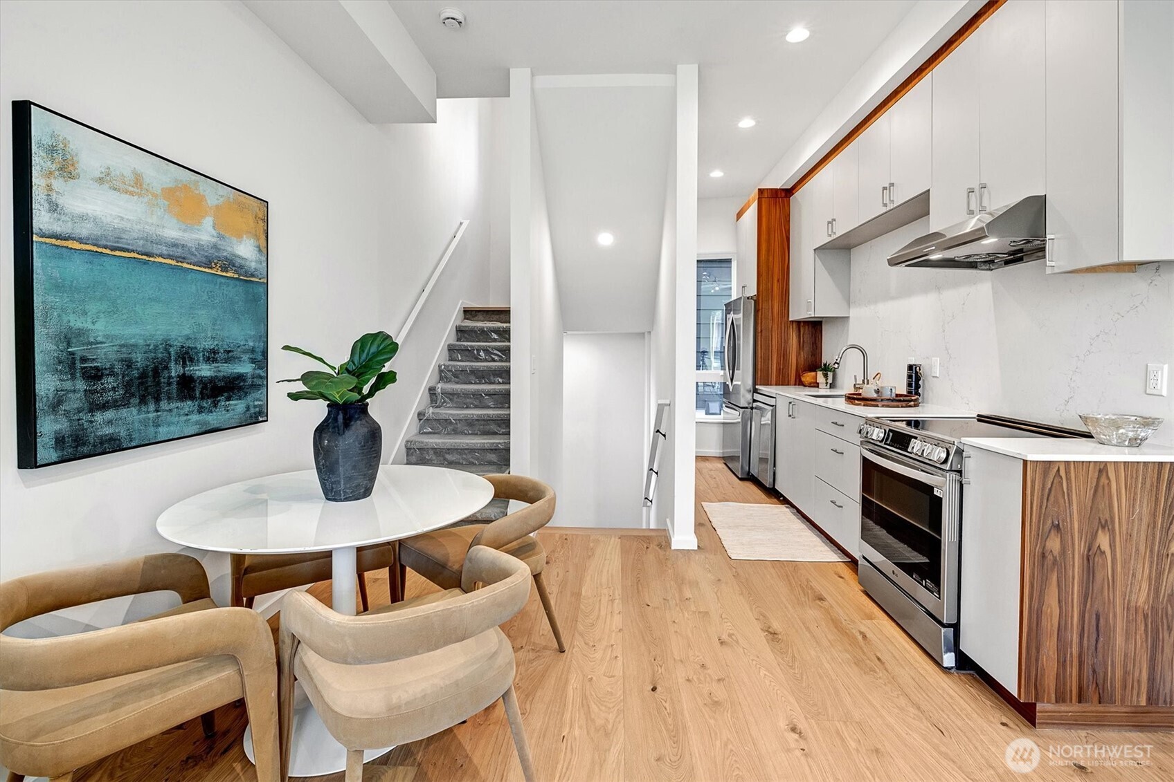 1227 East Roy Street Seattle, WA 98102 - Photo 12 of 35 a kitchen with stainless steel appliances kitchen island granite countertop a table chairs stove and wooden floor