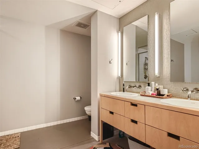 a bathroom with a double vanity sink toilet and mirror