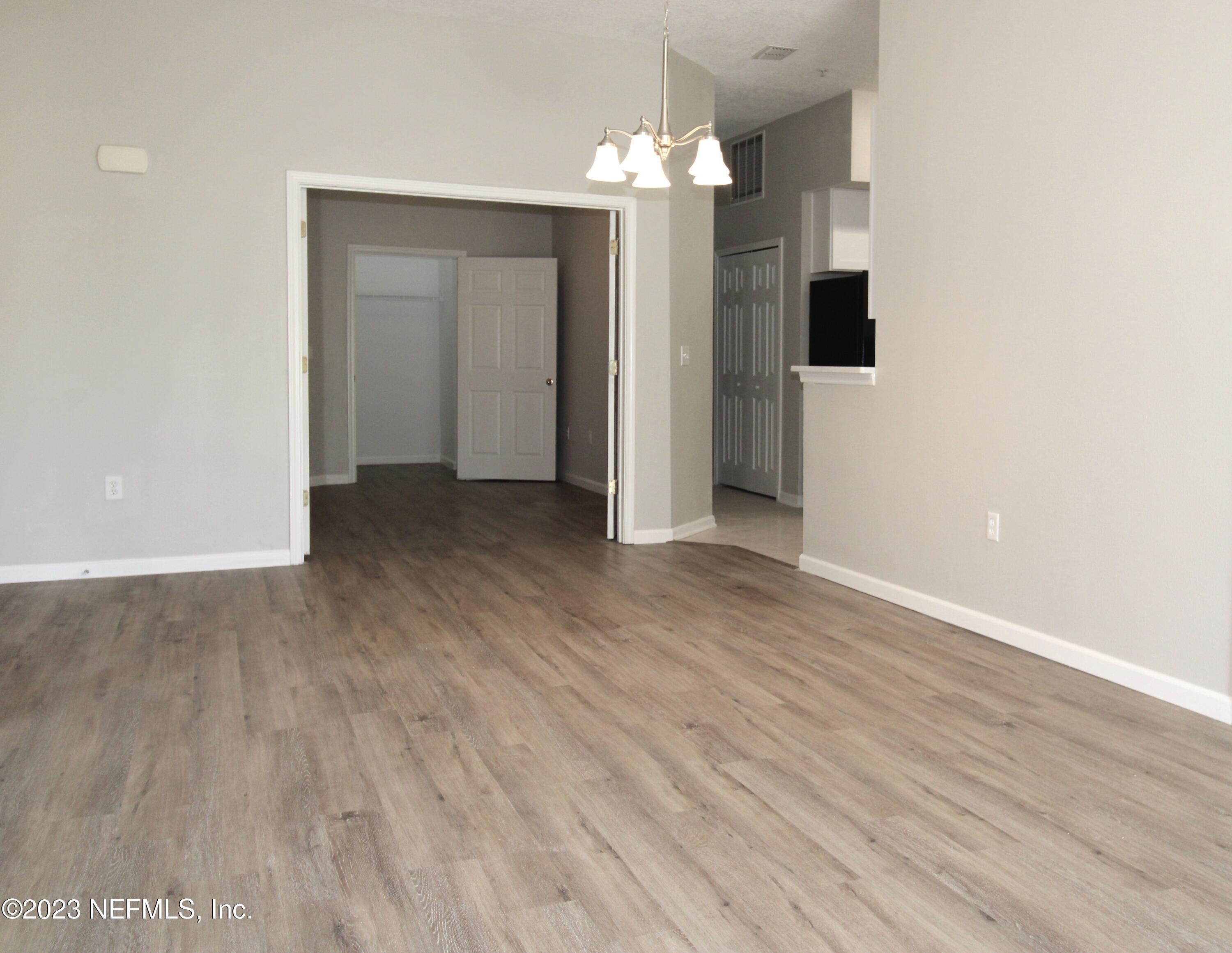416 Golden Lake Loop St. Augustine, FL 32084 - Photo 6 of 22 an empty room with wooden floor and chandelier