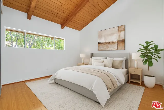 a bedroom with a bed lamp and potted plant on the counter