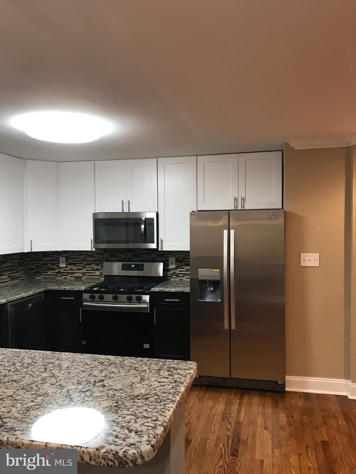 6710 Fox Meadow Road Baltimore, MD 21207 - Photo 24 of 24 a kitchen with granite countertop a refrigerator and a stove top oven