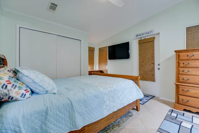 a bedroom with a bed and a flat tv screen on dresser