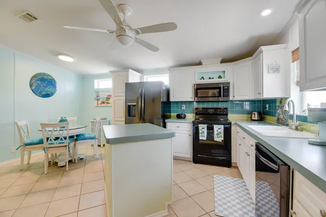 a kitchen with stainless steel appliances granite countertop a stove top oven a sink a dining table and chairs