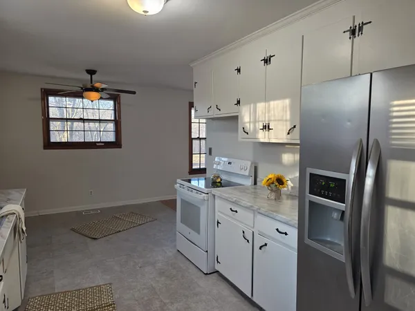 a kitchen with granite countertop white cabinets and white appliances