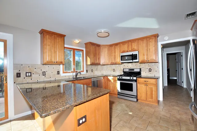 a kitchen with stainless steel appliances granite countertop a sink stove and refrigerator