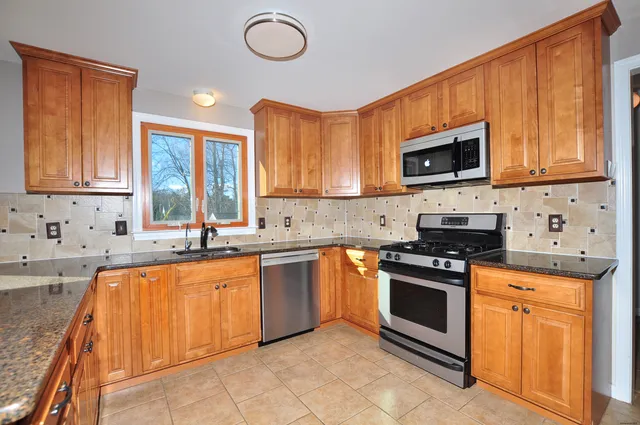a kitchen with stainless steel appliances granite countertop a stove top oven a sink dishwasher and a microwave oven on the blue kitchen countertops