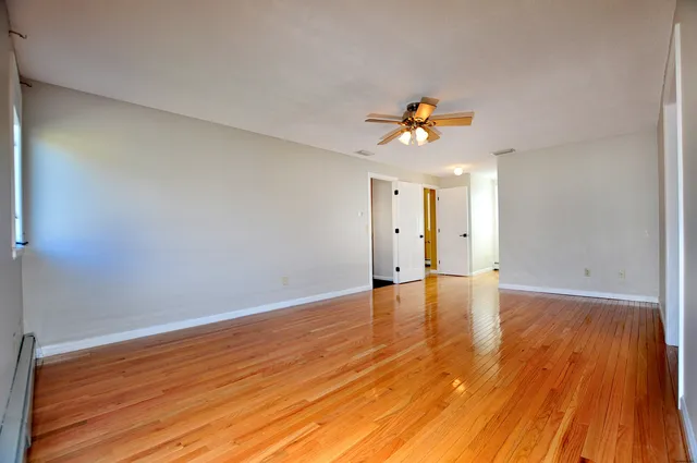 a view of a room with wooden floor and a ceiling fan